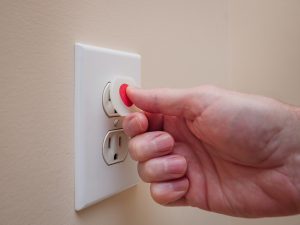 inserting plastic safety plug into outlet.