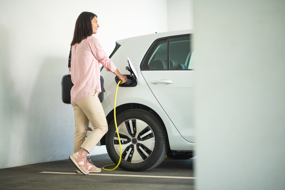 women charging an electric car.