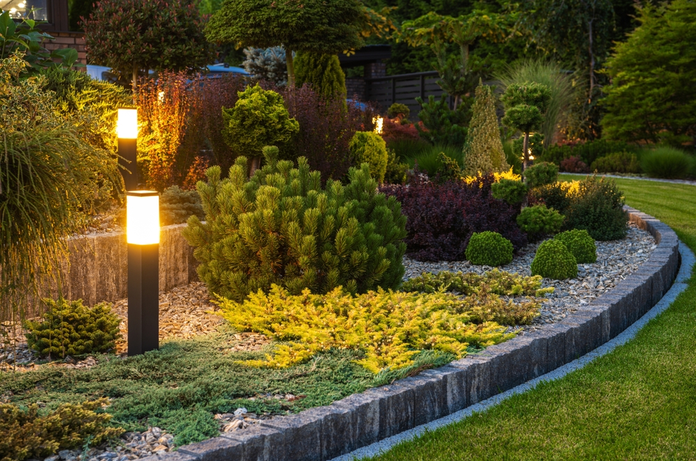 illuminated outdoor light fixture in landscaped flower bed.
