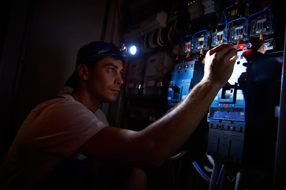 electrician working on electrical panel in a blackout.